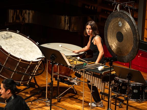 Studierende der Schlagzeugklasse sitzt in einem vielfältigen Setup aus Schlagzeuginstrumenten.