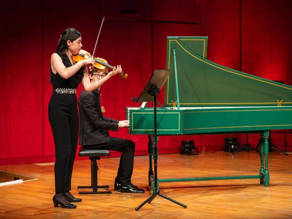Geiegnstudentin mit Cembalostudent musizieren auf dem Konzertsaalpodium.