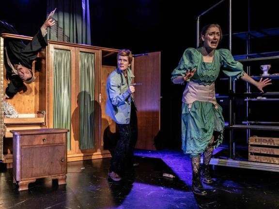 Spielszene mit drei Spieler*innen vor einem Schrank