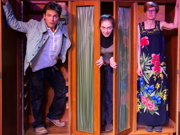 Zwei Schauspielerinnen und ein Schaspieler stehen in einem Schrank und gucken aus drei geöffneten Scvhranktüren heraus