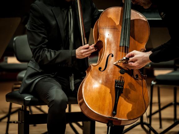 Ein Violoncello wird mit einem Mikrophon auf dem Steg präpariert.