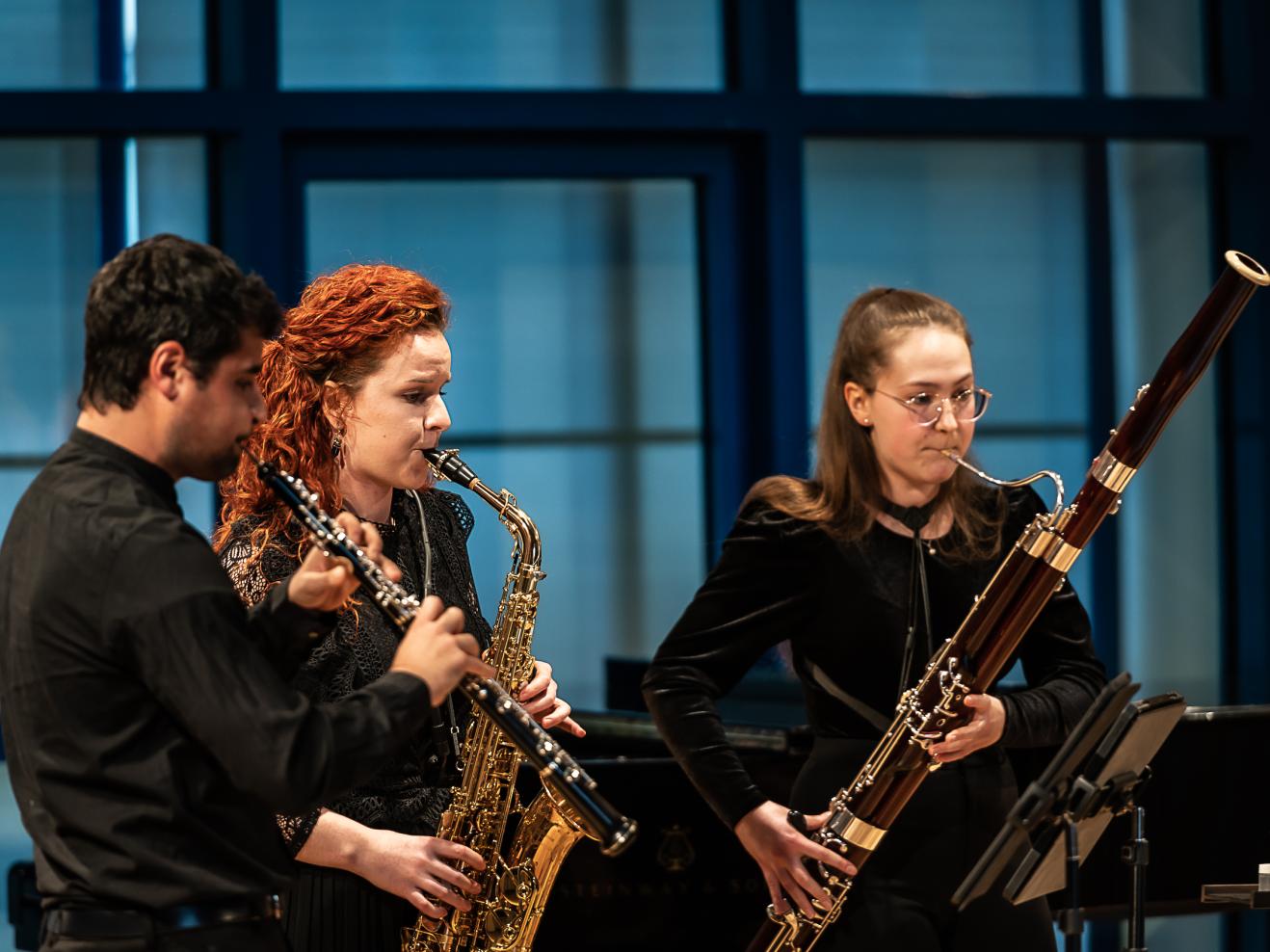 Drei Mitglieder des Sonus-Quintetts auf dem Podium des Orchesterprobenraums während einem Festivalauftritt.
